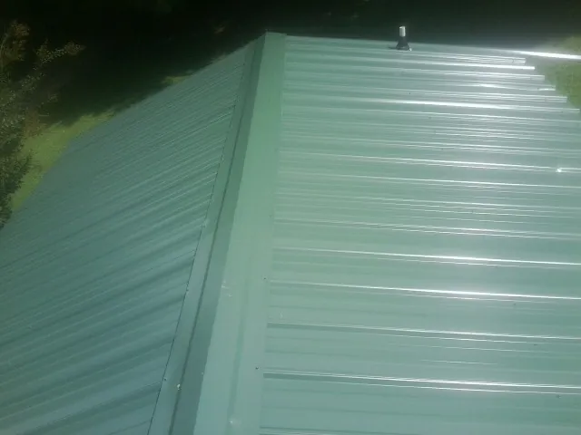 New green metal panels meeting at the ridge of a roof — Flat Roof Repair work by our crew in Dickey