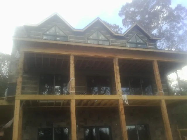 Dormers and porch framing on a large log home under construction — Roof Coating work by our crew in Dickey
