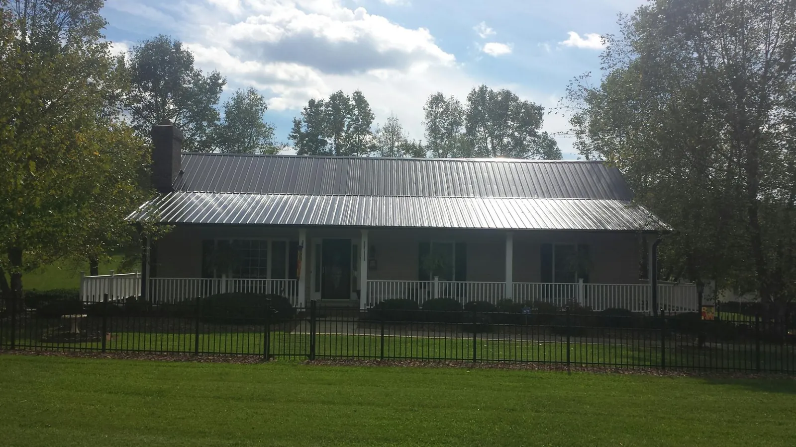 Gray metal roof on a brick ranch with a full width front porch — Gutter Guard Installation work by our crew in Dickey