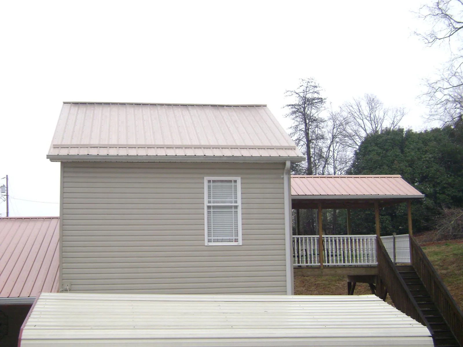 Tan metal roofs on a two story addition and attached porch in Dickey