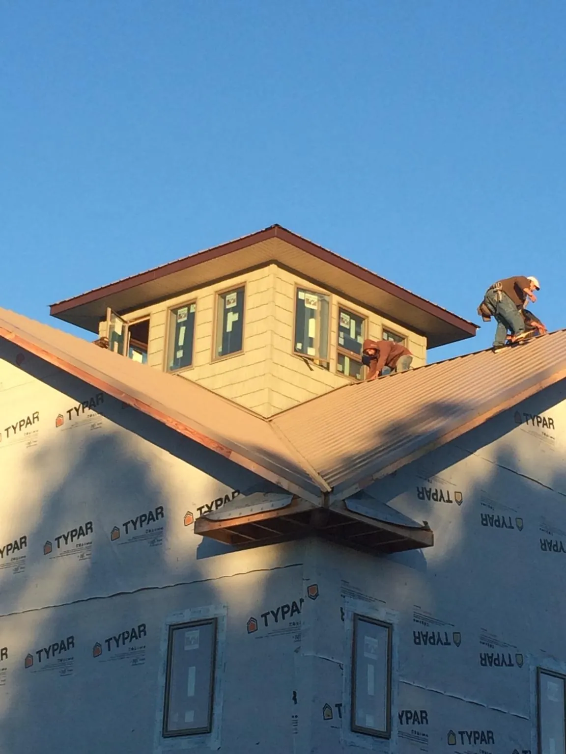 Roofers working around a rooftop cupola on a new metal roof at sunset — Roof Waterproofing in Dickey by Roofing Brothers